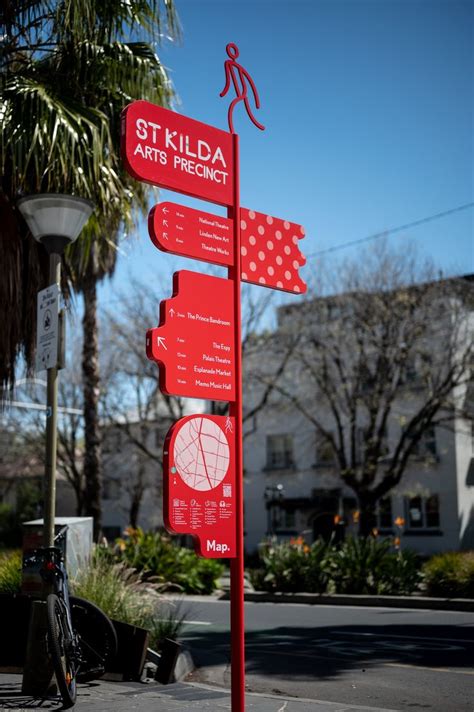 a red street sign sitting on the side of a road next to a palm tree