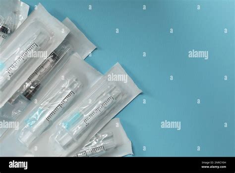 Packed Disposable Syringes With Needles On Light Blue Background Flat