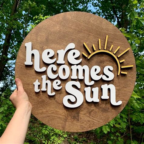 There Is A Wooden Sign That Says Here Comes The Sun