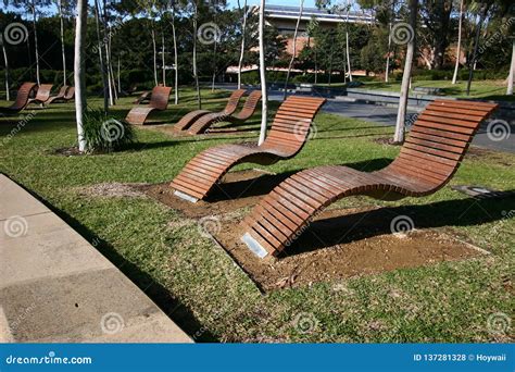 Empty Outdoor Wood Slat Chaise Lounge Chairs Hovering Above Grass In