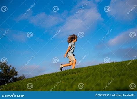 Happy Child Boy Runs Around The Green Field On Blue Sky Emotional Walk