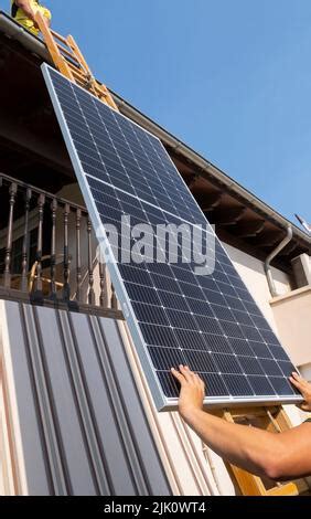 Worker Lifting Solar Panel Up Ladder To Rooftop Navarre Spain Europe