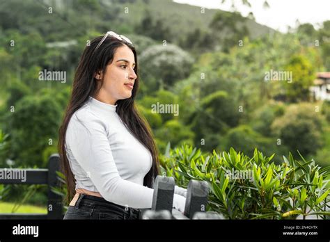 Latina Teenager Looking At The Scenery Standing Next To The Black Wooden Fence In The Open Air