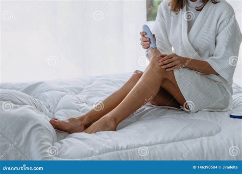 Donna Che Applica La Crema Della Lozione Sulle Sue Gambe Sul Letto In