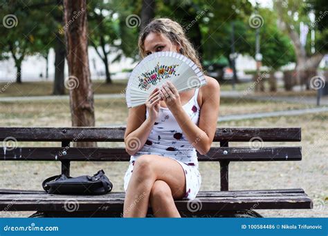 Attractive Blonde Girl Sitting On The Bench In A Park And Hiding Stock Photo Image Of Cooling