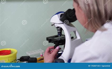 Female Research Scientist Looks At Biological Samples Under Microscope