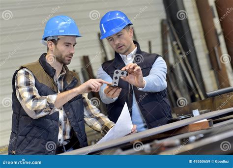 Engineer With Mechanical Worker Checking On Production Quality Stock