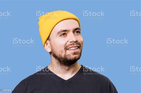 A Satisfied Male Figure Wearing A Yellow Cap In A Studio Shot With A