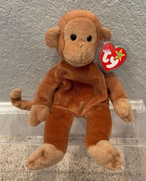 A Stuffed Monkey Sitting On The Floor In A Clear Plastic Container With