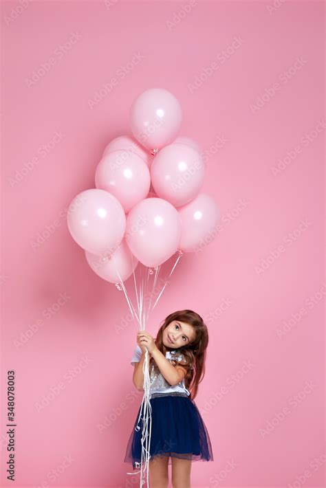 Smiling adorable little child girl posing with pastel pink air balloons ...