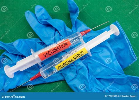 Syringes Labelled Corona Virus And Vaccination On Blue Rubber Gloves