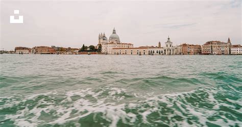 White And Brown Concrete Building Beside Body Of Water During Daytime Photo Free Travel Image