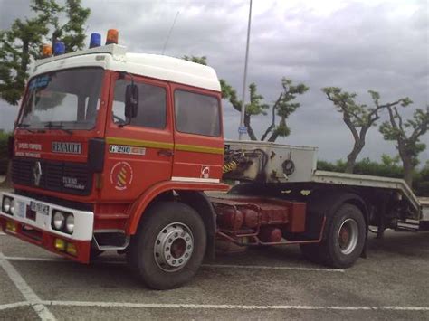 A Red And White Tow Truck Parked In A Parking Lot Next To Some Pine Trees