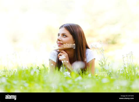 Beautiful young woman lying on grass with flowers Stock Photo - Alamy