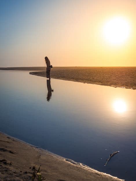 Bela foto de uma mulher caminhando na praia sob o sol Foto Grátis