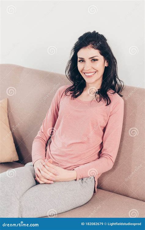 Beautiful Happy Woman Sitting On Couch And Looking At Camera At Home