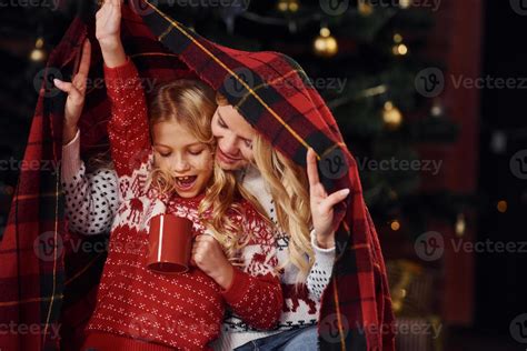 Mother And Daughter Sits Under Plaid With Ts Celebrating Christmas