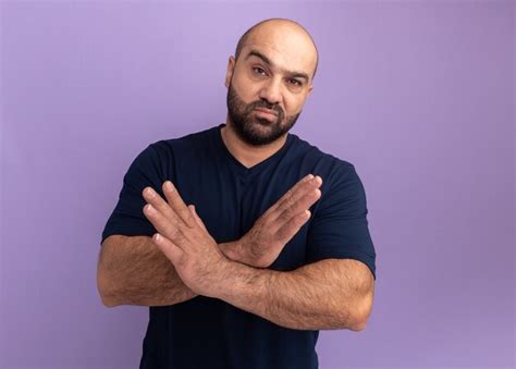 Hombre Barbudo En Camiseta Azul Marino Con Rostro Serio Cruzando Las