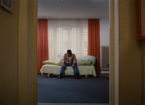 A Man Sitting On Top Of A Couch In A Living Room Next To A Window