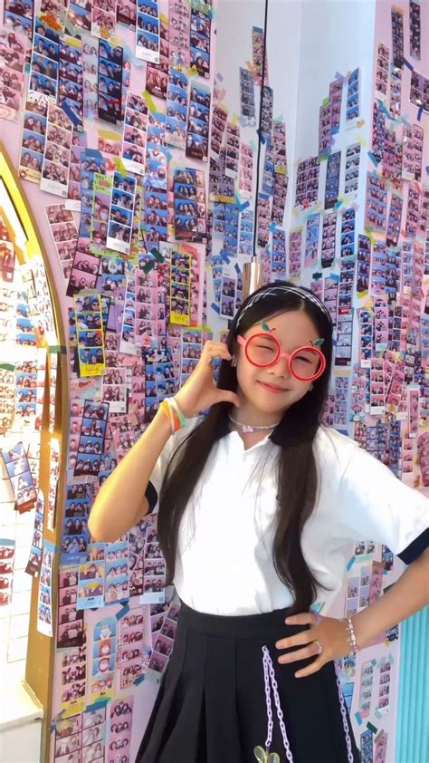 A Girl Wearing Glasses Standing In Front Of A Wall Covered With Stickers