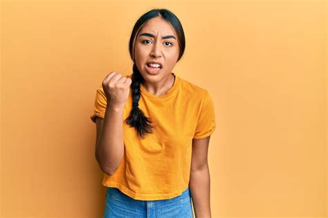 Joven mujer latina con ropa informal enojada y loca levantando el puño frustrada y furiosa