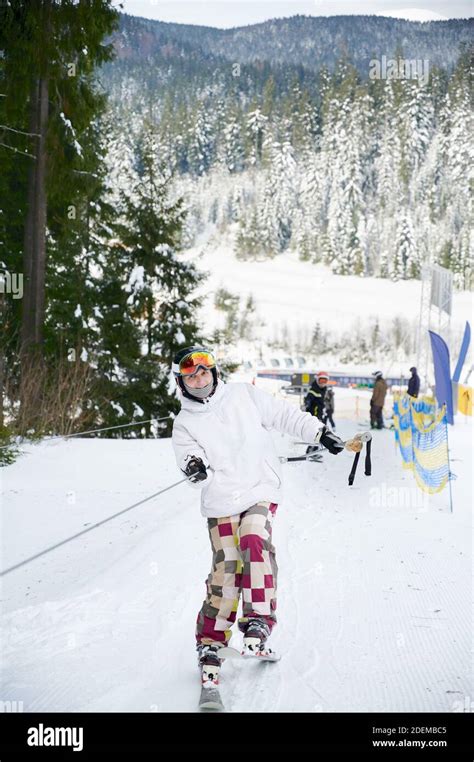 Tourist at ski resort lifting on the ski drag lift rope, trying to keep ...