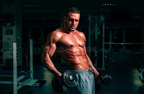 Bodybuilder In Gym Training And Workouts Dumbbells Exercises Sportsman With Naked Torso