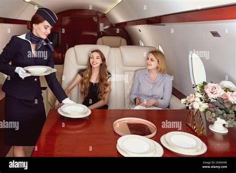 The Flight Attendant Serves The Passengers Of The Business Jet Stock