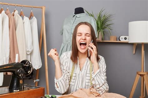 Costurera de mujer extremadamente feliz sonriendo hablando por teléfono