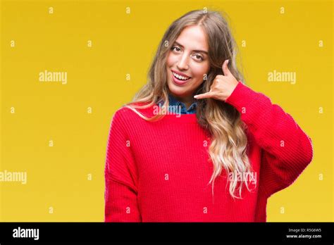 Schöne junge blonde Frau tragen winter Pullover über isolierte Hintergrund lächelnd tun Telefon