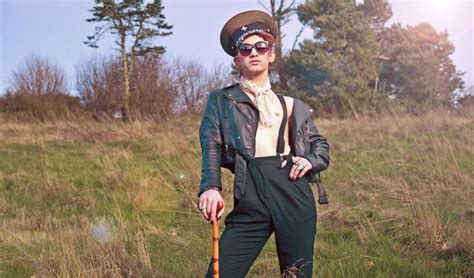 a woman wearing sunglasses and a hat holding a stick