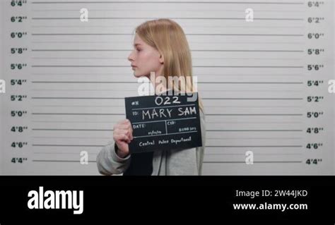 Mugshot Of Young Criminal Woman Holding Sign For Photo In Police