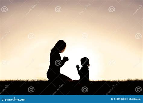 Mother Praying With Her Young Child Outside At Sunset Stock Photo