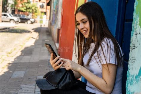 Bella Joven Latina Con Una Amplia Sonrisa Revisando Los Mensajes De Su Celular Imagen De Archivo