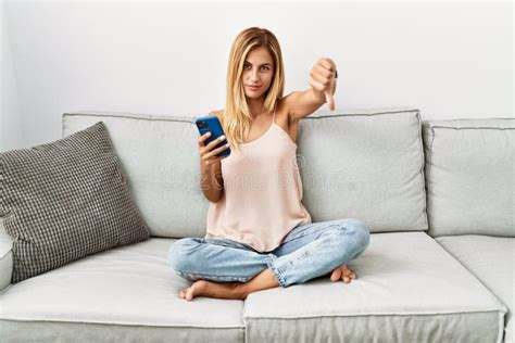 Blonde Belle Jeune Femme Assise Sur Le Canapé à La Maison à L aide De Smartphone à L air