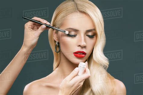 Gorgeous Blonde Woman Applying Makeup Isolated On Grey Stock Photo Dissolve