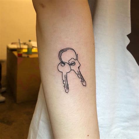 A Person With A Small Tattoo On Their Arm Holding A Key To The Lockhole