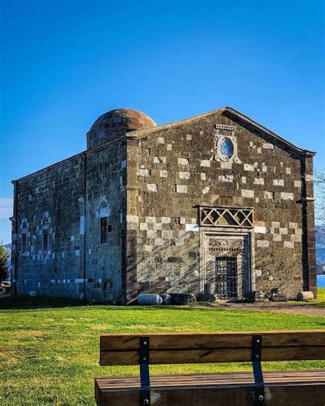 An Old Building With A Wooden Bench In Front Of It On A Grassy Area