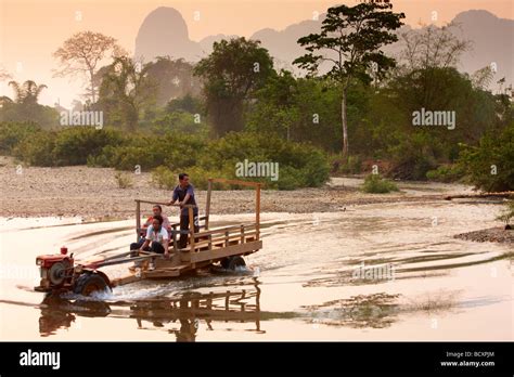 Un tractor Lao vadear un río al amanecer nr Vang Vieng en Laos