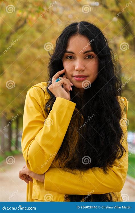 Young Latin Girl Dressed In Yellow Raincoat Posing Looking At Camera