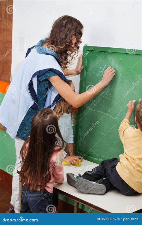 Teacher And Students Writing On Chalkboard In Stock Photo Image Of