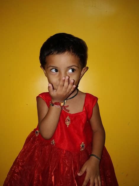 Premium Photo Cute Girl Wearing Red Dress While Standing Against Yellow Wall