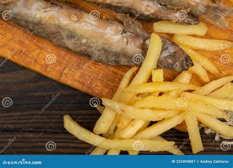 Peixe Frito E Batatas Fritas Num Quadro De Corte Numa Mesa De Madeira