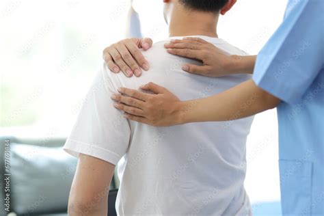 Doctor Diagnosing Mans Shoulder Pain In Hospital Examination Room