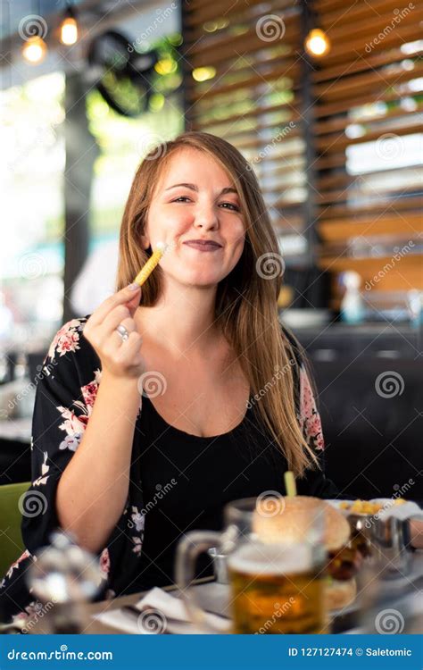 Muchacha Que Come La Hamburguesa En El Restaurante Foto De Archivo