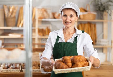 Female Baker In White Uniform Stands Behind Counter In Small Private Bakery Offering Hot