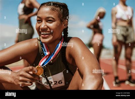 Female Runner With A Gold Medal Sitting On Track Running Race Winner