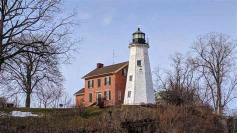 a lighthouse on top of a hill surrounded by trees