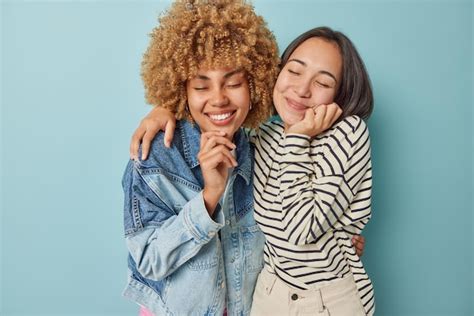 Tiro horizontal de mulheres multiétnicas sorriem alegremente abraçadas