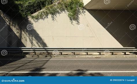 Metallic Guardrail On Sidewalk Concrete Wall Of An Underpass On Behind And Two Lane Road In